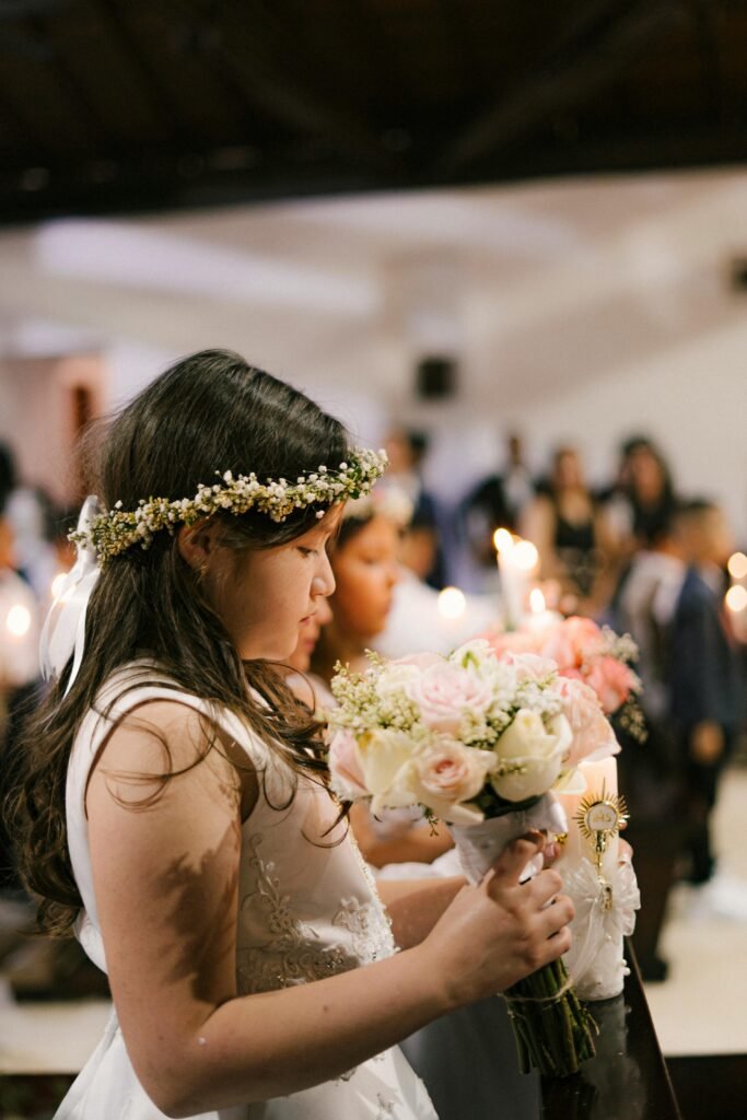 Young girl in first communion ceremony holding floral bouquet in church.