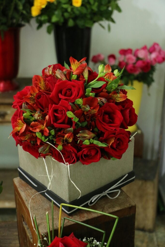 Elegant bouquet of red roses and orange lilies in a decorative box, perfect for gifting.