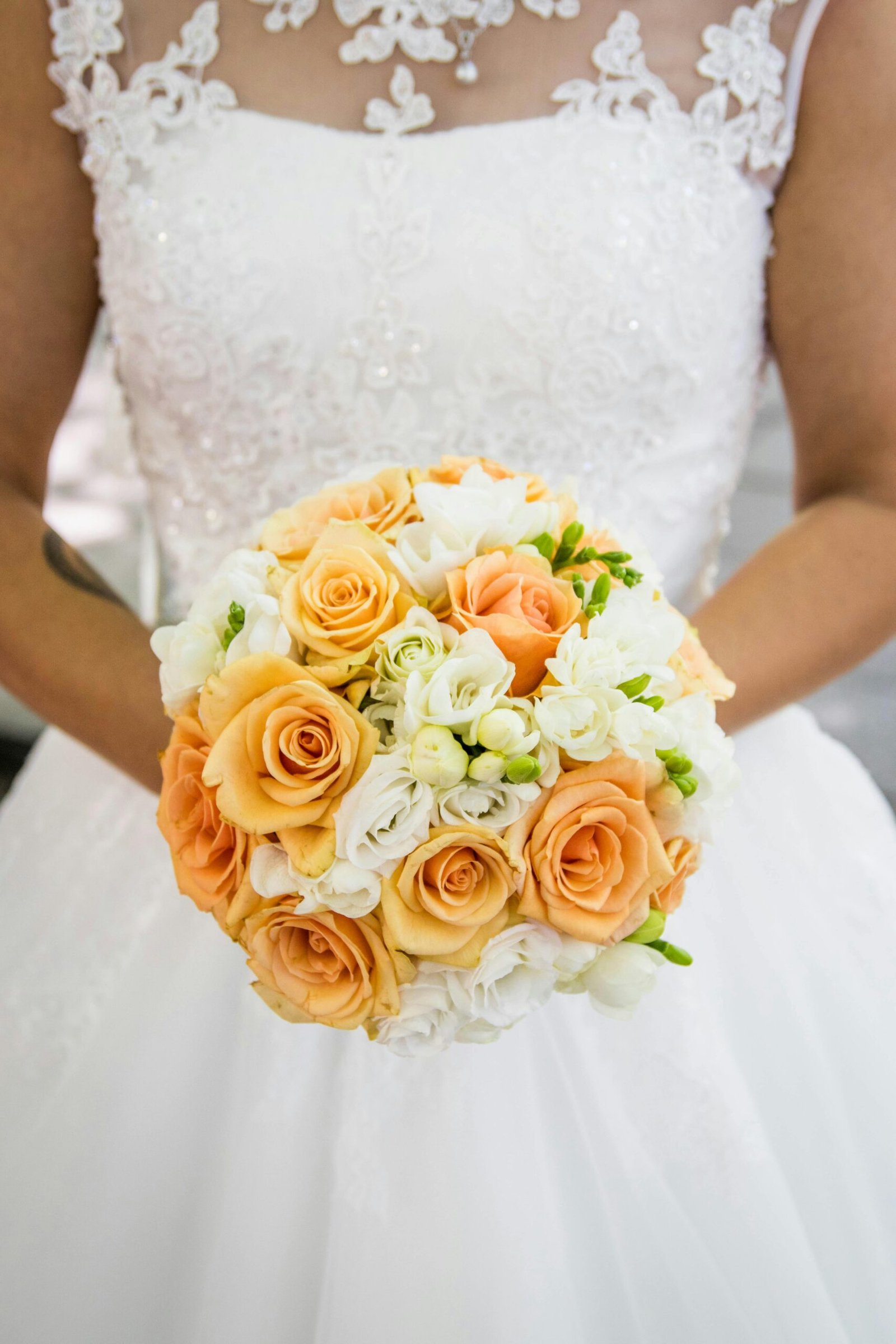pexels-photo-585410-585410 A bride holding an elegant bouquet of peach and white roses, ready for the wedding ceremony.